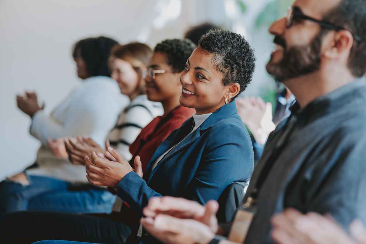 Group of people applauding in the audience of a business meeting