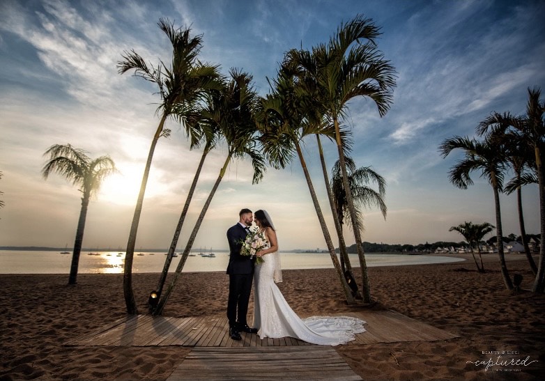 A groom and bride taking wedding photos on the beach at Anthony's Ocean View